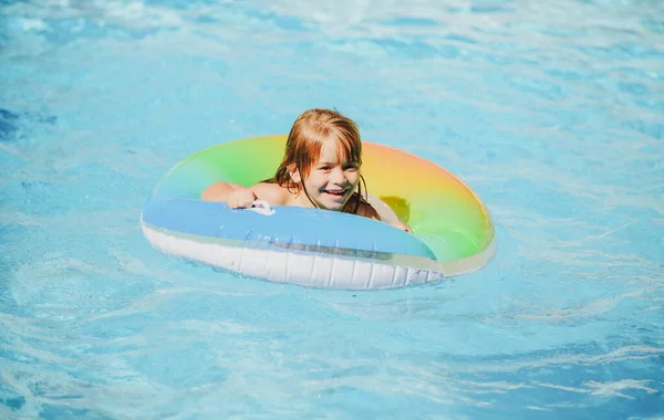孩子们在游泳池里，放松地在充气环上游泳，暑假在水里玩乐。健康的儿童生活方式. — 图库照片