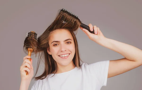 Mladá krásná žena česá hnědé vlasy. Péče o vlasy. Krásná brunetka žena kartáčování vlasů s kartáčkem na vlasy. Čištění zdravých vlasů hřebenem. — Stock fotografie