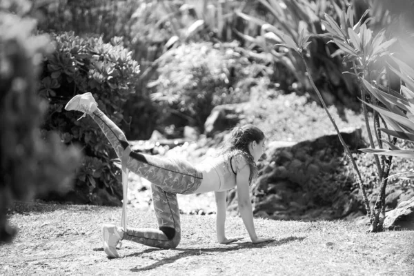 Fitness femme faisant des exercices d'étirement en plein air dans le parc. S'adapter corps sur nature. Fille athlétique faisant exercice de rebond avec bande de résistance. Fitness femme séance d'entraînement sur la nature. — Photo