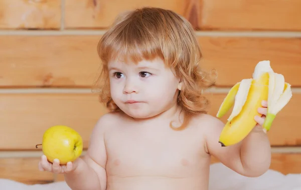 幸せな赤ちゃんの子供はリンゴとバナナを食べる. — ストック写真