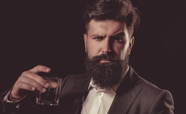 Hipster com barba e bigode no terno bebe álcool após o dia de trabalho. Bebida de uísque tradicional velha - bebida de cavalheiros. Whisky elegante. — Fotografia de Stock