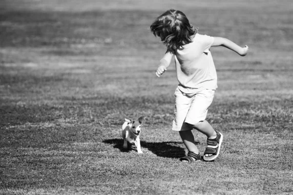 Szczęśliwy dziecko chłopiec biegać z a pies zewnątrz. — Zdjęcie stockowe