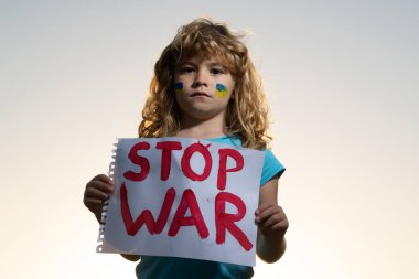 Çocuklar savaşı protesto ediyor. Küçük sarışın çocuk savaşı durdurun diyor, yazıyla bayrağı kaldırıyor, savaşı durdurun. Kelimelerle tabelayı tutan çocuk dışarıda duran savaşı durdurun..