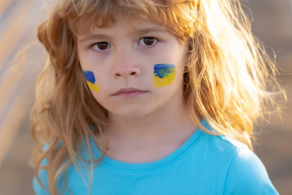 子供の頬にウクライナの旗。戦争も戦争もロシアの侵略も。ウクライナ人の愛国者. — ストック写真