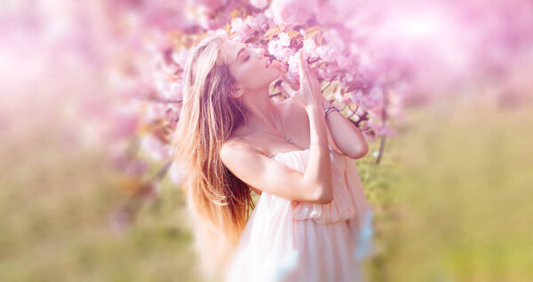 Beautiful spring young woman outdoors enjoying spring. Beautiful young woman near blooming spring tree. Youth, love, fashion, romantic and lifestyle concept