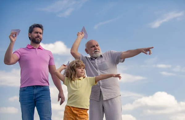 Tři generace mužů pohromadě, portrét usmívajícího se syna, otce a dědečka s letadýlkem. Chlapec si hraje s letadlem a sní o budoucnosti. Koncept cestovní cesty. — Stock fotografie