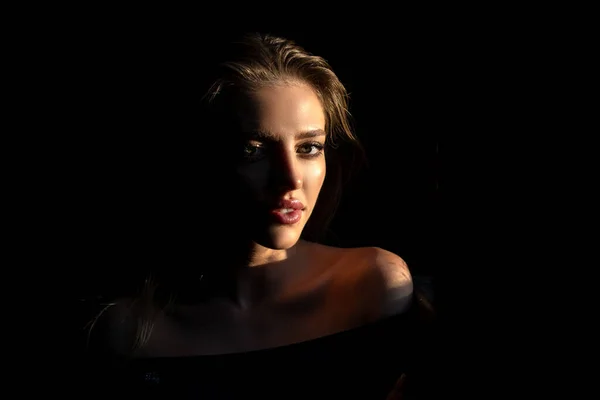 Jonge vrouw poseert in de studio over zwarte achtergrond. Licht en schaduw. Modeportret van een mooie vrouw met donker licht op het gezicht. Dramatisch licht op sensuele verleiding vrouw gezicht. — Stockfoto