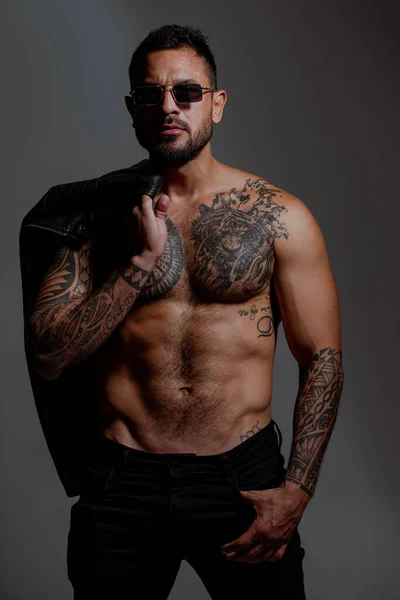 Fashion and sexy male model. Seductive face of a sexy man. Macho looking confident. Fashion male model, vogue style. Tattooed and elegant hipster.