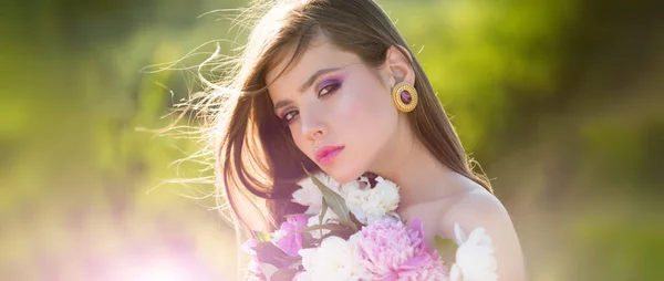Naturligt skönhetsansikte. Ung vacker sexig bekymmerslös kvinna poserar på våren bakgrunden. Sommarmodell med blommor i händerna utomhus. — Stockfoto