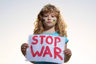 Çocuk savaşı protesto ediyor. Portre çocuk savaşı durdurun diyor, yazıyla bayrağı kaldırıyor savaşı durdurun.
