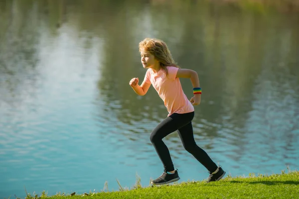 Çocuk koşucular parkta koşar. Sportif genç çocuk dışarıda koşuyor ve antrenman yapıyor.. — Stok fotoğraf