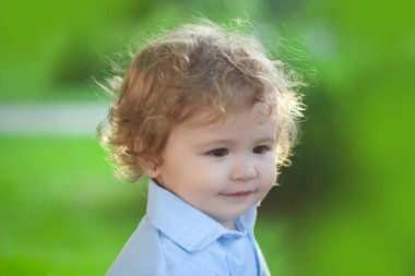 Yeşil çimenlerde oynayan bir bebek. Bebek yüzü yakın plan. Komik küçük çocuk, yakın plan portre. Sarışın çocuk, duygusal yüz..