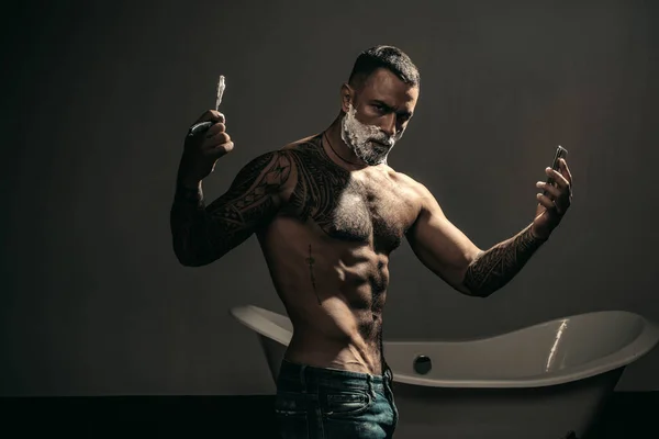 Tipo sexy afeitándose la barba. Cuchilla de barbero. Hombre con navaja vintage. Cepillo de afeitar con crema espuma. — Foto de Stock