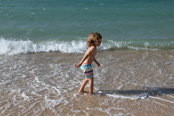 Ragazzo che salta tra le onde del mare. Salta dagli spruzzi d'acqua. Vacanze estive per bambini. — Foto Stock