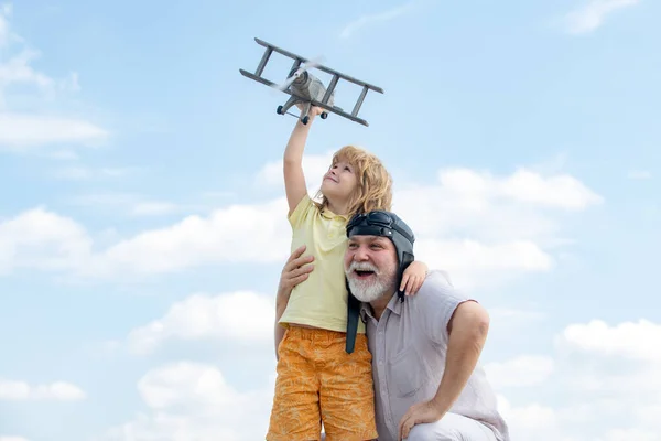 Menino e avô brincando com avião juntos no céu azul. Criança bonito com o avô brincando ao ar livre. Gerações idades. — Fotografia de Stock