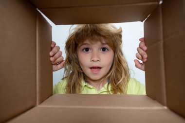 7 yaşındaki süpriz çocuk bavulunu açtı, kutusunu açtı ve içine baktı. Paket, teslimat, sürpriz, çocuk için hediye. Çocuk duyguları ve çocuk yüz ifadeleri.
