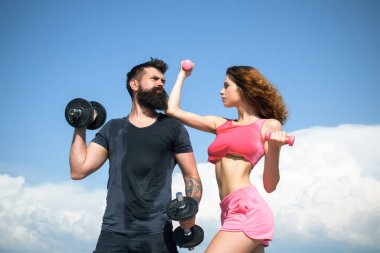 Dışarıda dambılları olan sağlıklı bir çift atletik erkek ve kadın. Dışarıda spor yapan bir çift. Genç fitness çifti.
