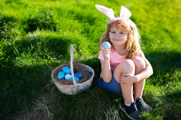 Pasen mand Gelukkig Pasen voor kinderen. Jongen in konijnenoren met kleurrijke eieren spelen en jagen buiten op paaseieren. Paaseieren jacht. — Stockfoto