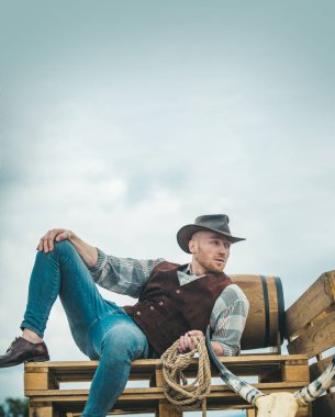 Kovboy çiftçisi kovboy şapkası takıyor. Çiftliğin kırsal kesimindeki Amerikan erkek modeli. Erkekler eski moda, eski moda, vahşi erkek model..