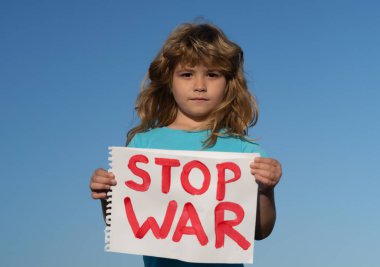Çocuk savaşı protesto ediyor. Portreci çocuk savaşı durdurun diyor, yazıyla bayrağı kaldırıyor savaşı durdurun. Kelimelerle tabelayı tutan çocuk dışarıda duran savaşı durdurun..