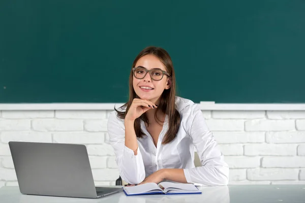 Portré fiatal női főiskolai tanuló szemüvegben tanuló osztályteremben laptop osztályban táblagéppel háttér. — Stock Fotó