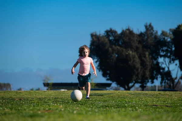 Piłkarzyki, dziecko grające w piłkę na świeżym powietrzu. Młody chłopak z piłką kopie. Piłkarze w ruchu. Słodki chłopak w akcji sportowej. Piłka nożna dla dzieci. — Zdjęcie stockowe