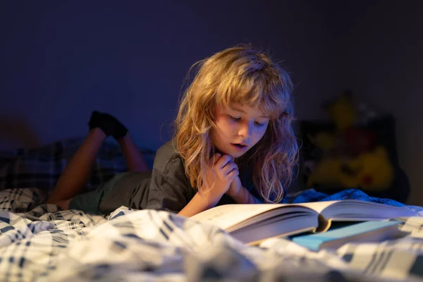 Barn läser en bok i sängen innan de somnar. Barn läser en bok om sänggåendet. Pojken läser godnattsaga, sagan. Barn läser böcker. — Stockfoto