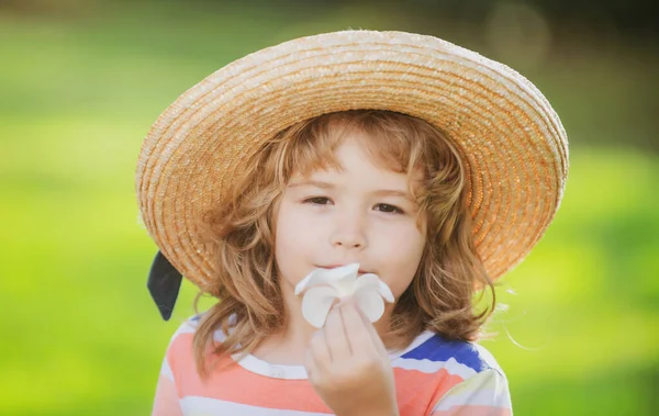 Retrato de un niño lindo en sombrero de paja que huele a flor de plomería. Cara de niños caucásicos de cerca. Primer plano de chico gracioso. — Foto de Stock