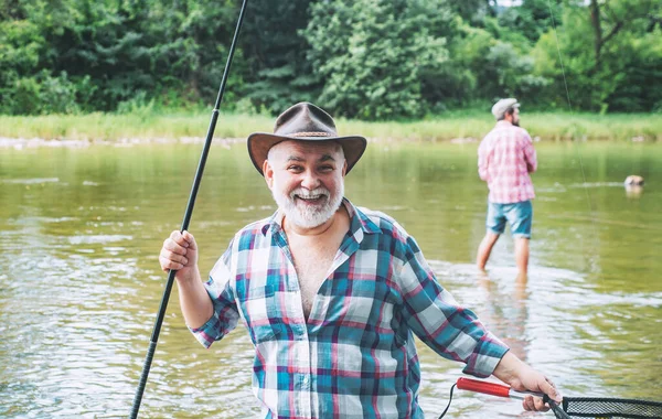 Männer angeln im Fluss während des Sommertages. Glückliche Fischer angeln im Fluss mit Angelruten. Forellen am Haken. Fisch am Haken. — Stockfoto