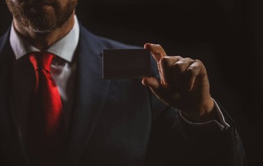 Kredi kartı sahibi bir iş adamı. Elinde boş bir kredi kartı modeli var. Kredi kartı el ele tutuşmanın şablonunu oluşturur. Banka kartı. Ticari marka.