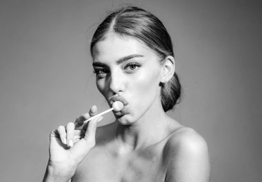 Kırmızı dudaklı, lolipop tutan seksi bir kadın. Güzellik abidesi. Stüdyoda şehvetli kadın portresi.