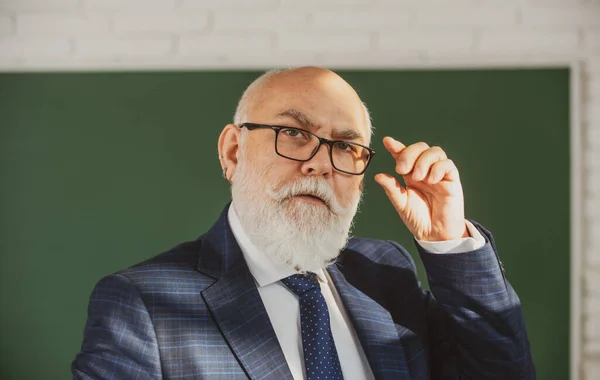 Profesor anciano en una pizarra en blanco durante la lección, dando clases en la universidad. Piensa en senior. Día del maestro. —  Fotos de Stock