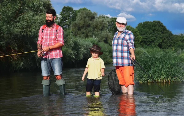 Buon nonno e nipote stanno pescando sul fiume. Padre, figlio e nonno si rilassano insieme. Un hobby maschile. Weekend estivo. — Foto Stock