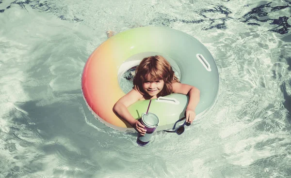 Mały chłopiec w okularach przeciwsłonecznych i letni koktajl relaksujący się pierścieniem zabawki pływającym w basenie. — Zdjęcie stockowe