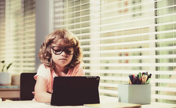 Miúdo na escola online, escola em casa. Ensino à distância. Menino alegre usando tablet laptop estudando através do sistema de e-learning online. — Fotografia de Stock