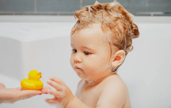 Kleines Kind wäscht sich die Haare in der Badewanne. Schaumbad für Kinder. — Stockfoto