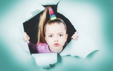 Kağıt delikten dışarı bakan kız çocuğu. Pankart. Mutlu kız. Mavi kağıtta delik deşik olmuş kız görüntüsü. Reklam için alanı kopyalayın, metin ya da slogan eklemek için. İndirim, satış. Çocuk portresi. Yakın plan..