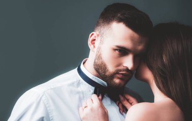 Kadın, erkeğin papyonunu, papyonunu tutuyor. Aşık seksi bir çift. Şehvetli aşıklar soyunur. Kız arkadaş ve erkek arkadaş şehvetli kucaklaşmalar. Erkek kıza romantik kucaklaşma. Şefkatle sarıl. Çıplak tutku vücudu.