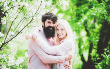 Mutlu Paskalya tatili konsepti. Çift gülüyor ve sarılıyor. Çiçek açan ağaç bahçesinde birbirine aşık gülümseyen bir çift..