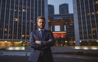 Ofisin dışında duran kendinden emin bir iş adamının portresi. İş yerinin dışında kolları kavuşturulmuş gülümseyen iş adamı CEO 'su. İyi giyimli iş adamı..