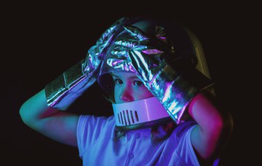 Astronot kaskı giymiş küçük bir çocuk ve... Astronotun içinde oynayan ve uzay adamı olmayı hayal eden sevimli bir çocuk. Neon renkli çocukların yüzlerini kapat.
