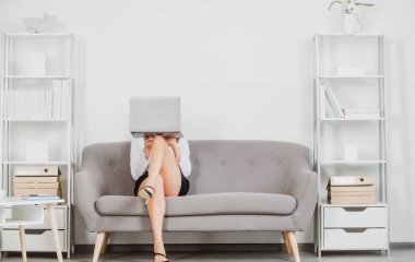 Seksi bacaklı baştan çıkarıcı sekreter ofiste kanepede oturur. Seksi iş kadını yüzünü dizüstü bilgisayarla kapatıyor. Şehvetli kız çalışanı. Güzel sekreter bacakları.