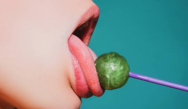Kadın ağzında lolipop, kırmızı ruj. Kırmızı, parlak bir lolipopu yalayan bir kadın. Kapatın. Şehvetli ağzında lolipopu olan seksi kadın..