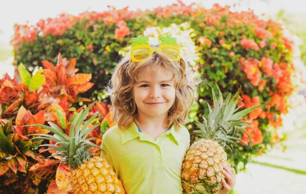 Een jongetje met een glimlachende ananas in de tuin. Zomervruchten. — Stockfoto