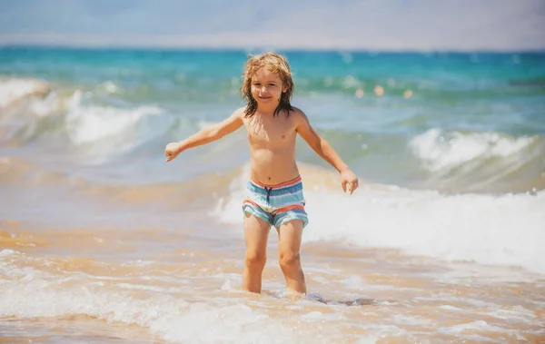 Menino na costa. Um miúdo a brincar no oceano. Férias no mar. A criança em ondas. — Fotografia de Stock