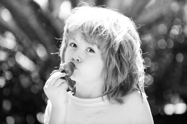 Щасливий маленький хлопчик їсть полуницю на зеленому літньому тлі . — стокове фото