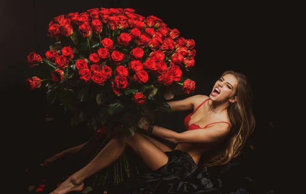 Mulher sensual sexy com buquê de rosa. Menina em lingerie vermelha com Valentines presente. Presente com amor. — Fotografia de Stock