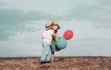 Çocuklar mavi gökyüzü arka plan karşı alanda eğleniyor. Aşk hikayesi. Mutlu çocuklar kız ve erkek doğada yaz aylarında çayır sarılmak. Sevgililer günü kartı.