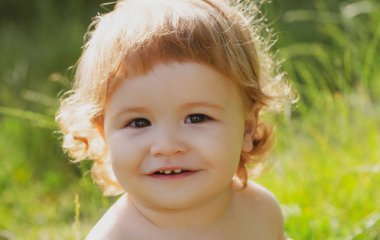 Çocuk yaz bahçesinde aile pikniğinde eğleniyor. Bebek yüzlü, yakın çekim. Küçük komik çocuk portresi. Sarışın çocuk, duygusal yüz..