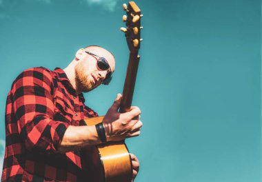 Gökyüzünde gitar çalan yakışıklı genç adam. Kamp tatili.